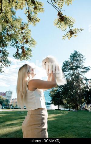 Woman lifting fluffy Pomeranian in park Stock Photo