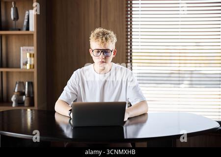 Young person focused on laptop in modern workspace during daytime Stock Photo
