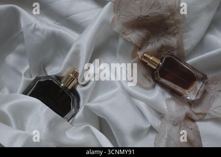 two perfume bottles on white silk background Stock Photo