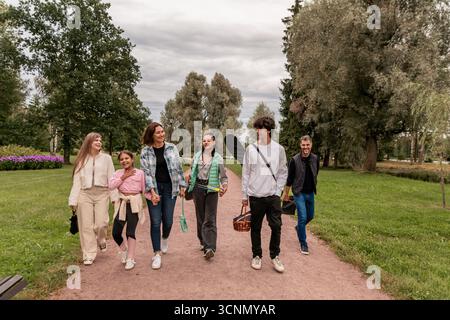 Happy family walking along park path after picnic. Stock Photo