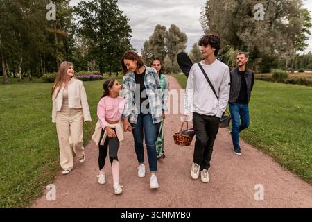 Happy family walking along park path after picnic. Stock Photo