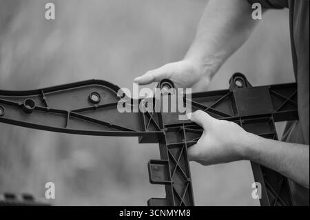 Close-up of hands carefully connecting sections of a black plastic component. The intricate design is evident. A focus on precision and manufacturing. Stock Photo
