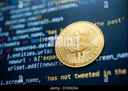 Close-up of golden Bitcoin cryptocurrency coin on computer code background representing blockchain technology and digital finance. Stock Photo