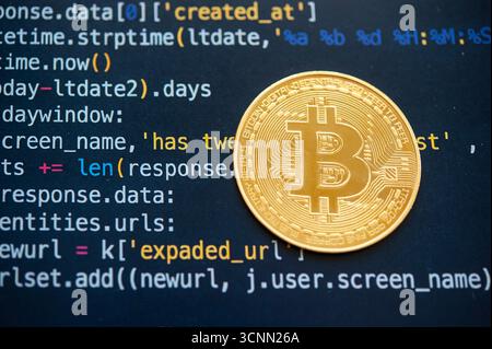 Close-up of golden Bitcoin cryptocurrency coin on computer code background representing blockchain technology and digital finance. Stock Photo