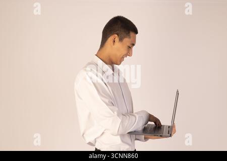 Man in white shirt and black pants holding laptop Stock Photo