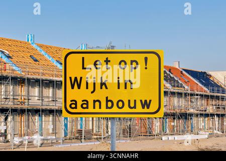 Sign with the Dutch text for "Attention - Residential area under construction" in front of new family homes in The Netherlands Stock Photo