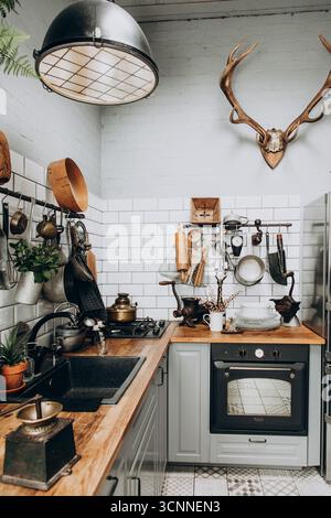 This inviting kitchen features wooden countertops, stylish cookware, and decorative items. The combination of vintage elements with modern appliances Stock Photo