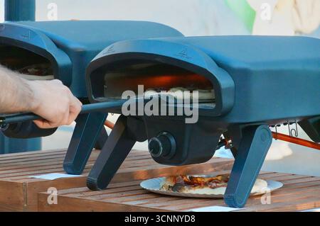 A man is cutting a piece of pizza with a rotary saw. Stock Photo