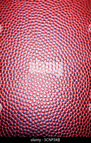 A close-up of an American football reveals detailed leather texture and precise stitching, photographed in a studio against a black background, highli Stock Photo