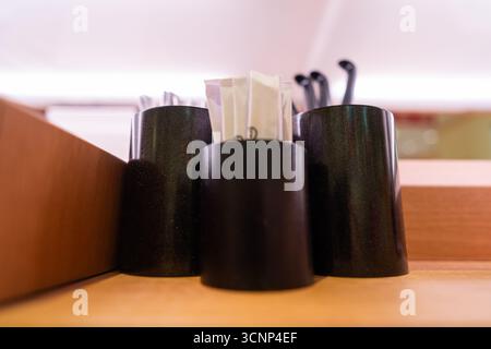 Black cylindrical containers holding cutlery and napkins on a wooden surface - West Lake in Huizhou, Guangdong Province, China, is a tourist attraction featuring ancient architecture Stock Photo
