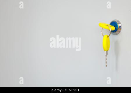 Yellow key in lock on modern door close-up. Real estate or rental idea symbolized by key in lock. Stock Photo