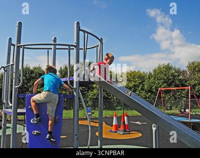 Two small boys playing on a slide. Stock Photo