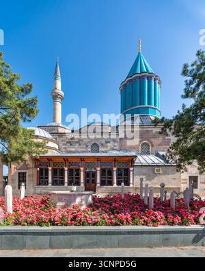 Mevlana Museum, Turkish: Mevlana Muzesi, with its distinctive green dome and minaret, surrounded by vibrant red roses, in Konya, Turkey Stock Photo
