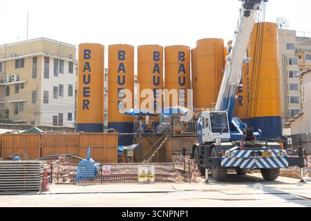 a construction site with several large yellow and blue Bauer silos and a crane. Bangkok, Thailand Stock Photo