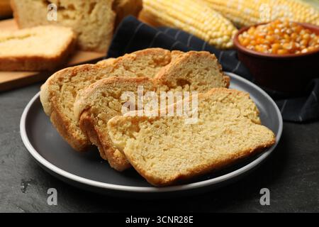 Freshly baked cornbread, cobs and seeds on black table, closeup Stock Photo