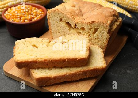 Freshly baked cornbread, cobs and seeds on black table, closeup Stock Photo