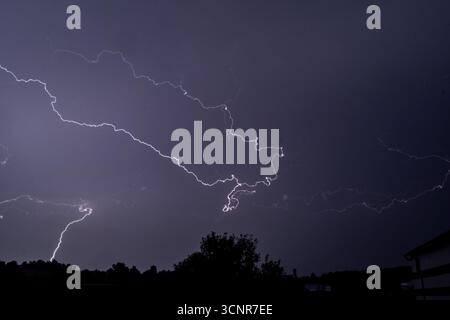 Flashes Of Lightning Illuminate The Night Sky as a powerful Thunderstorm passes through Stock Photo