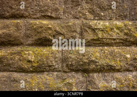 An old stone block wall with a little moss growing on it. Stock Photo