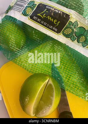 Still life of a bag of Trader Joe's limes on a yellow cutting board and a sliced lime, 2025, United States Stock Photo