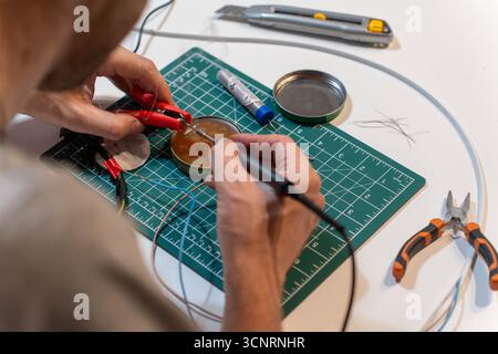 Hands working on electronic experiment with wires and soldering tools Stock Photo