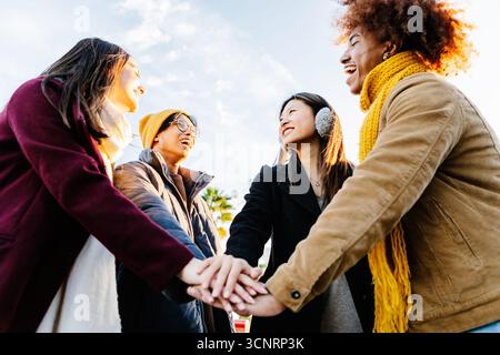 Multiracial happy friends with hands in stack at city street Stock Photo