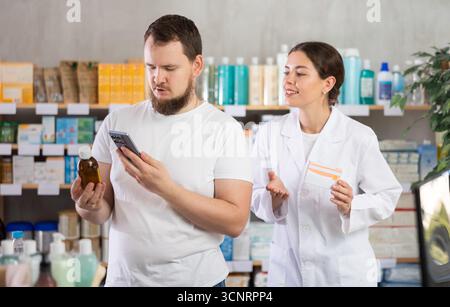 Man buyer scans syrup qr code with woman pharmacist Stock Photo