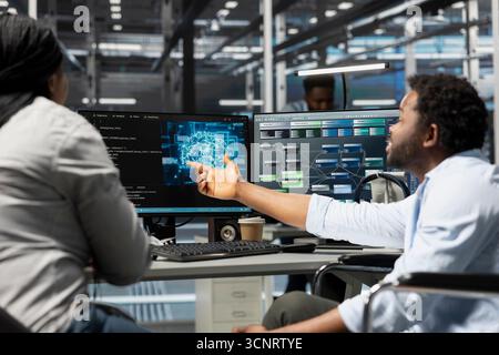 Data center manager and engineer with paraplegia using artificial intelligence computerized model. Server room team leader and worker in wheelchair using machine learning AI algorithms Stock Photo