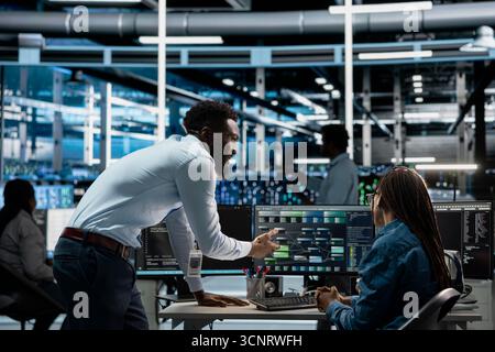 Data center admins programming infrastructure used for machine learning training. Server hub IT professionals collaborating running code on PC to upgrade artificial intelligence systems Stock Photo