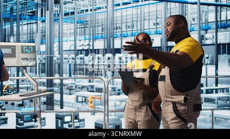 Photovoltaics smart factory staff members using tablet, researching PV materials. Industry 4.0 solar panels plant african american engineers developing alternative energy systems prototypes, camera A Stock Photo