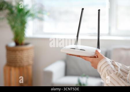 Woman with modern wi-fi router at home, closeup Stock Photo
