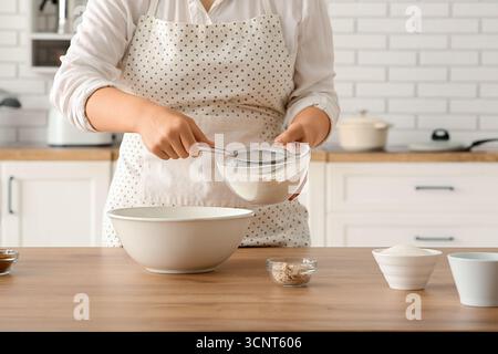 Woman preparing traditional cinnamon rolls in kitchen Stock Photo