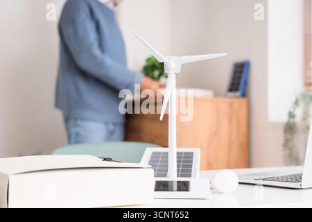 Wind turbine model with light bulb on engineer's table in office, closeup Stock Photo