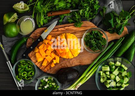 Prepped Ingredients for Mango Herb Salad: Sliced mango with cilantro, mint, jalapeno peppers, lime, scallions, and mini cucumbers Stock Photo