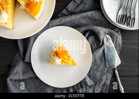 Slice of Mango Mousse Cake on a Plate Overhead View: Piece of swirled mousse cake with with cake server, forks, and cake stand in the background Stock Photo