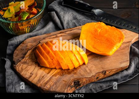 Slices of Mango on an Olive Wood Cutting Board: Closeup view of a juicy mango that has been peeled, cored, and sliced Stock Photo