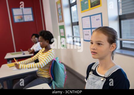 Diverse classmates sitting at desks in classroom using pencils, typing on laptop, copy space Stock Photo