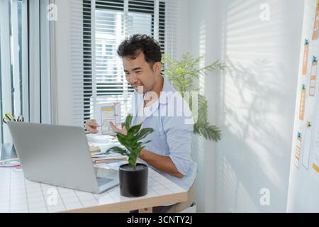 A focused designer is working on UX/UI design ideas, analyzing color palettes and interface structures pinned on a board. The scene reflects creativit Stock Photo