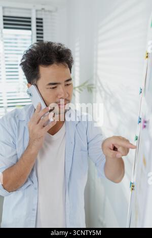 A creative designer is working on UX UI planning, reviewing wireframes, and adjusting color schemes for a mobile application project, showing focus an Stock Photo