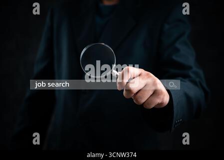 Businessman hand holding a magnifying glass searching or applying for a job. Stock Photo