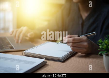 Female hand holding a pen to write goals or take diary notes on the desk Stock Photo