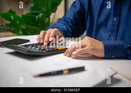 A man is working, using a calculator, doing accounting or financial transactions, banking or taxes. Stock Photo
