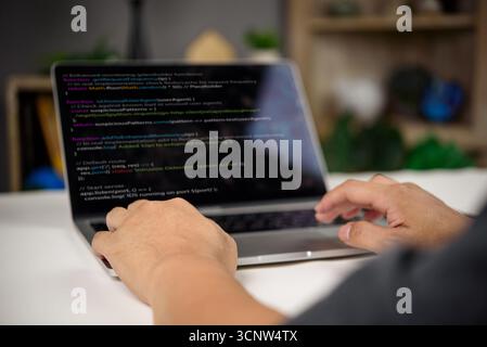 Developer working on intrusion detection system code in JavaScript with real-time monitoring and enhanced security features on laptop. Stock Photo