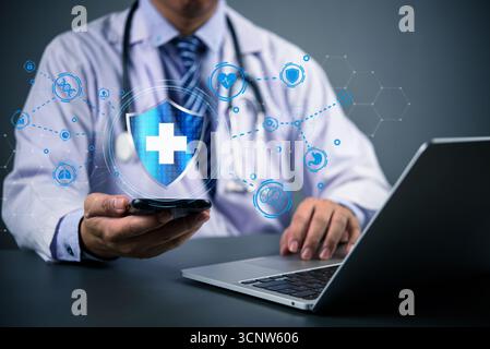 Doctor using smartphone and laptop with digital medical icons and shield symbol. Concept of digital health, telemedicine, and online data cybersecurit Stock Photo