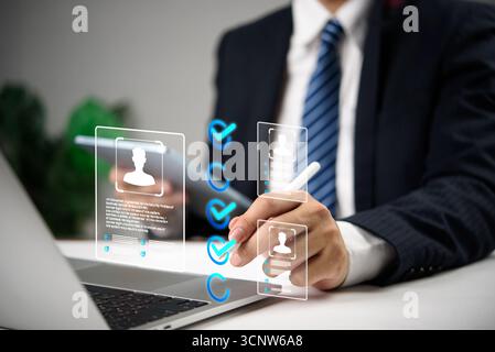 Businessman using digital interface to select candidates with virtual profile icons and checkmarks, representing modern recruitment, HR human resource Stock Photo