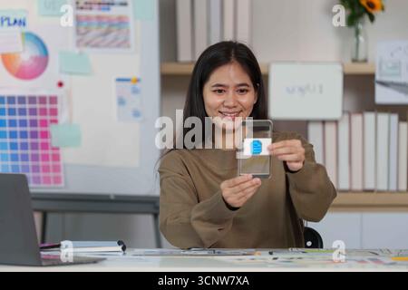 Smiling Designer Showcasing Mobile App Interface on Smartphone. Stock Photo