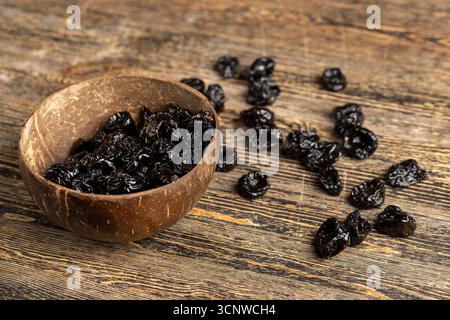 dry prunes made from ripe blue plums in a coconut shell plate, dried plums in a bowl made from natural materials Stock Photo