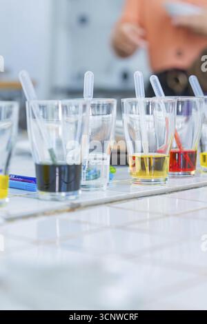 Several glasses on a table filled with colourful liquids and pipettes ready for an experiment, Youth Research Centre Stock Photo