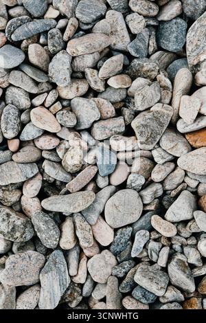 A macro photograph capturing a variety of smooth, rounded pebbles. These stones, with their earthy tones and diverse textures, showcase the natural be Stock Photo