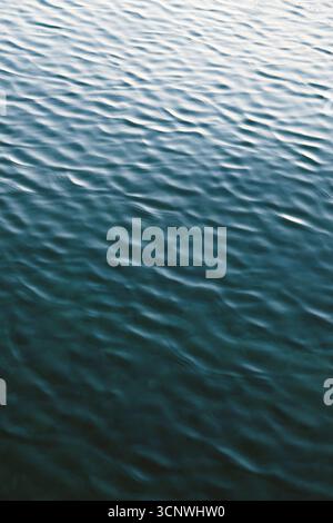 Macro photography capturing the intricate texture of small sea waves in motion, creating a mesmerizing pattern on the water surface under natural ligh Stock Photo