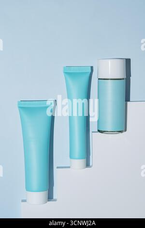 Minimalist design showcasing cosmetic packaging on a blue background. The geometric shapes create a modern, clean aesthetic, highlighting elegance and Stock Photo